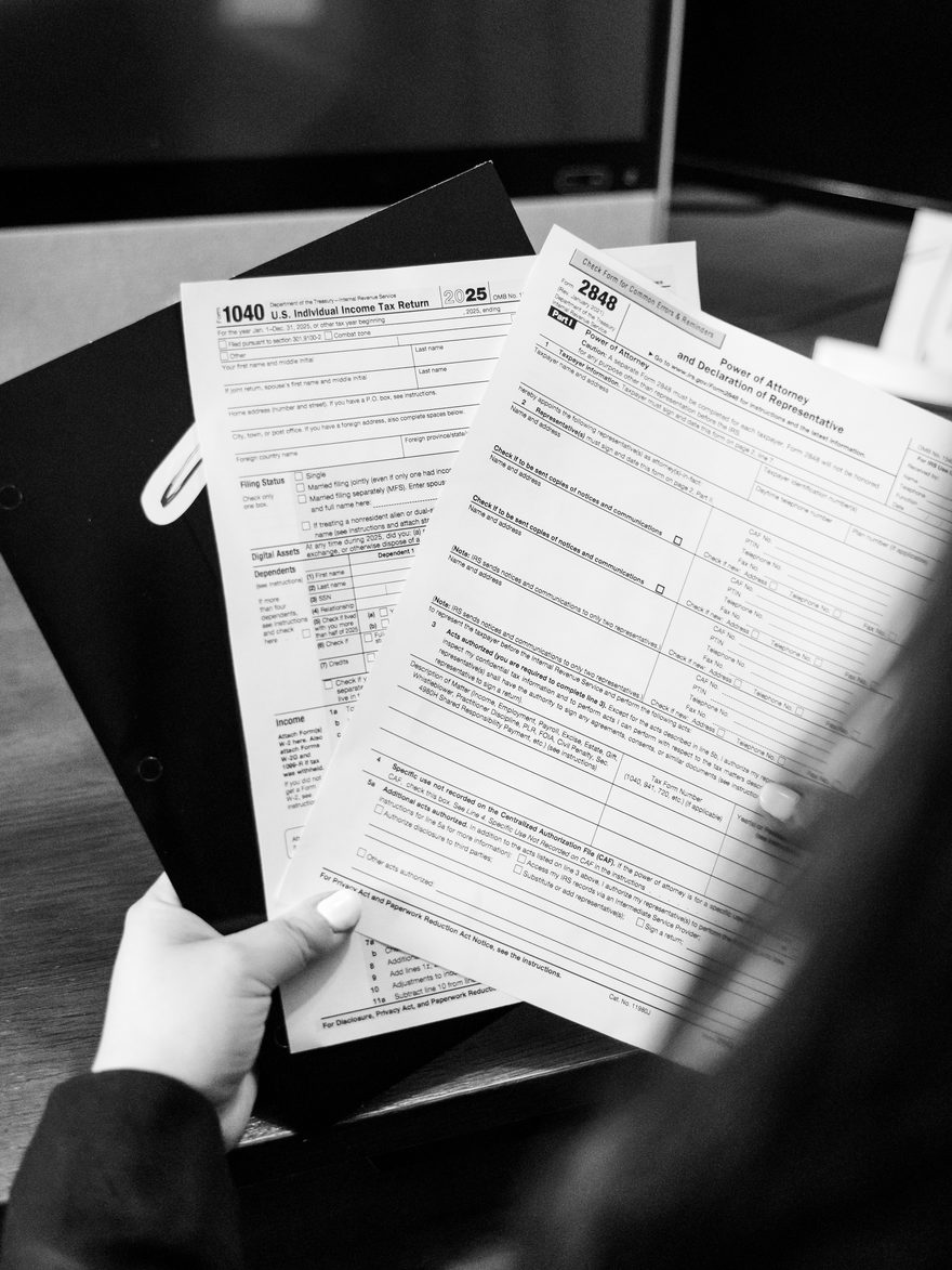Hands reviewing an IRS Form 1040 individual return and Form 2848 Power of Attorney